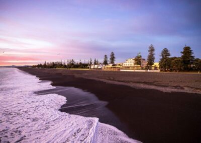 Voyage de Luxe en Nouvelle-Zélande : Coucher de soleil sur la plage de sable noir à Napier.