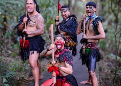Voyage Nouvelle-Zélande en famille : Groupe de quatre guerriers maoris en costume traditionnel et tatouages dans la nature