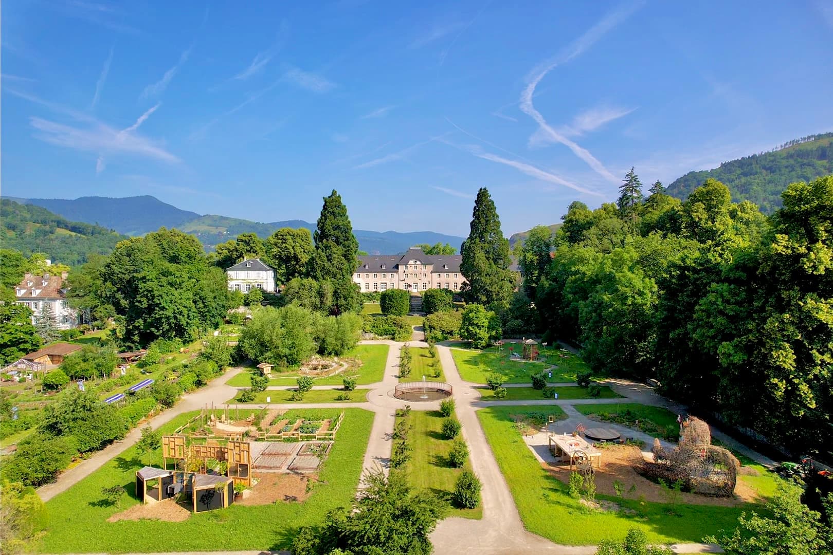 Séminaire sur mesure dans les Vosges : Vue aérienne des jardins du Parc de Wesserling avec le château au cœur des Vosges