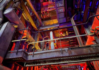 Séminaire sur mesure dans les Vosges : Intérieur de la Grande Chaufferie du Parc de Wesserling, avec tuyauterie, passerelles métalliques et éclairage coloré lors du spectacle son et lumière.