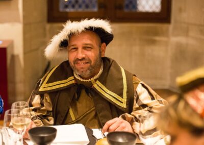 Soirée en château : le sourire d'un damoiseau lors d'un banquet costumé renaissance.