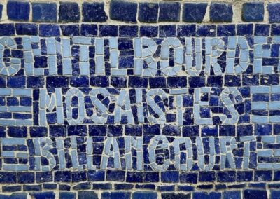 Voyage sur mesure en Auvergne : Enseigne mosaïque ovale "Maison Rozier" en tons dorés et bruns, encadrée par une balustrade en fer forgé.