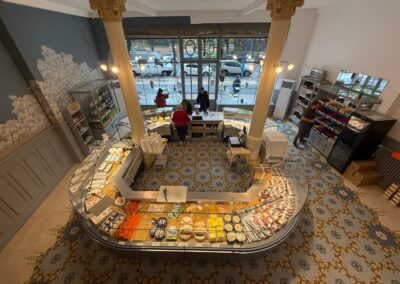 Visite hors des sentiers battus en Auvergne : Vue en hauteur de l'intérieur de la Maison Rozier à La Bourboule, montrant le comptoir arrondi en mosaïque avec des fromages et de la charcuterie.