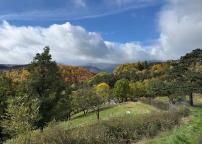 Escapade entre amis en Auvergne : Vue panoramique sur une vallée boisée aux couleurs automnales, ciel bleu et nuages, près de Murol.