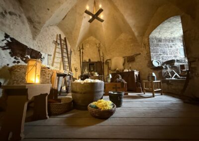 Voyage sur mesure en Auvergne : Salle voûtée du château de Murol meublée en style médiéval avec armes et mobilier d'époque.