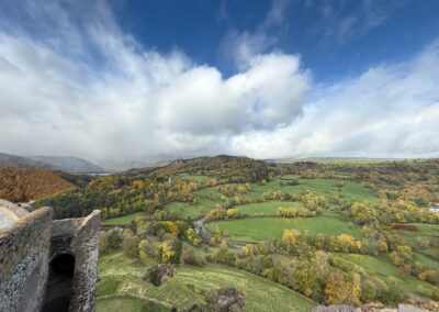Escapade entre amis en Auvergne : Panorama sur la vallée verdoyante et les collines depuis les remparts du château de Murol.