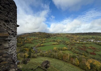Séjour familial en Auvergne : Vue depuis une tour du château de Murol sur la vallée boisée et les prairies.