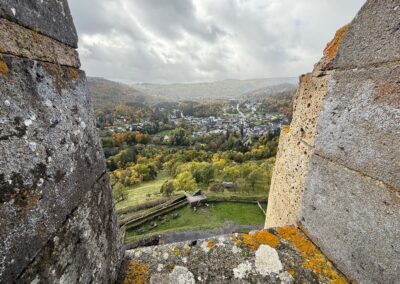 Visite hors des sentiers battus en Auvergne : Vue du village de Murol encadrée par les créneaux du donjon du château.