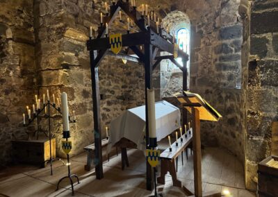 Séjour familial en Auvergne : Chapelle médiévale du château de Murol avec catafalque (estrade), cierges et blasons armoriés.
