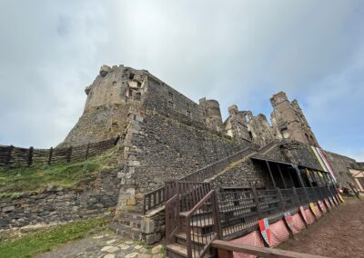 Séminaire original en Auvergne : Vue extérieure du château de Murol depuis la lice, avec ses tours et remparts en pierre volcanique.