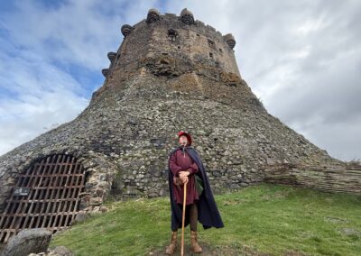 Séjour familial en Auvergne : Guide en costume médiéval devant le donjon en pierre du château de Murol.