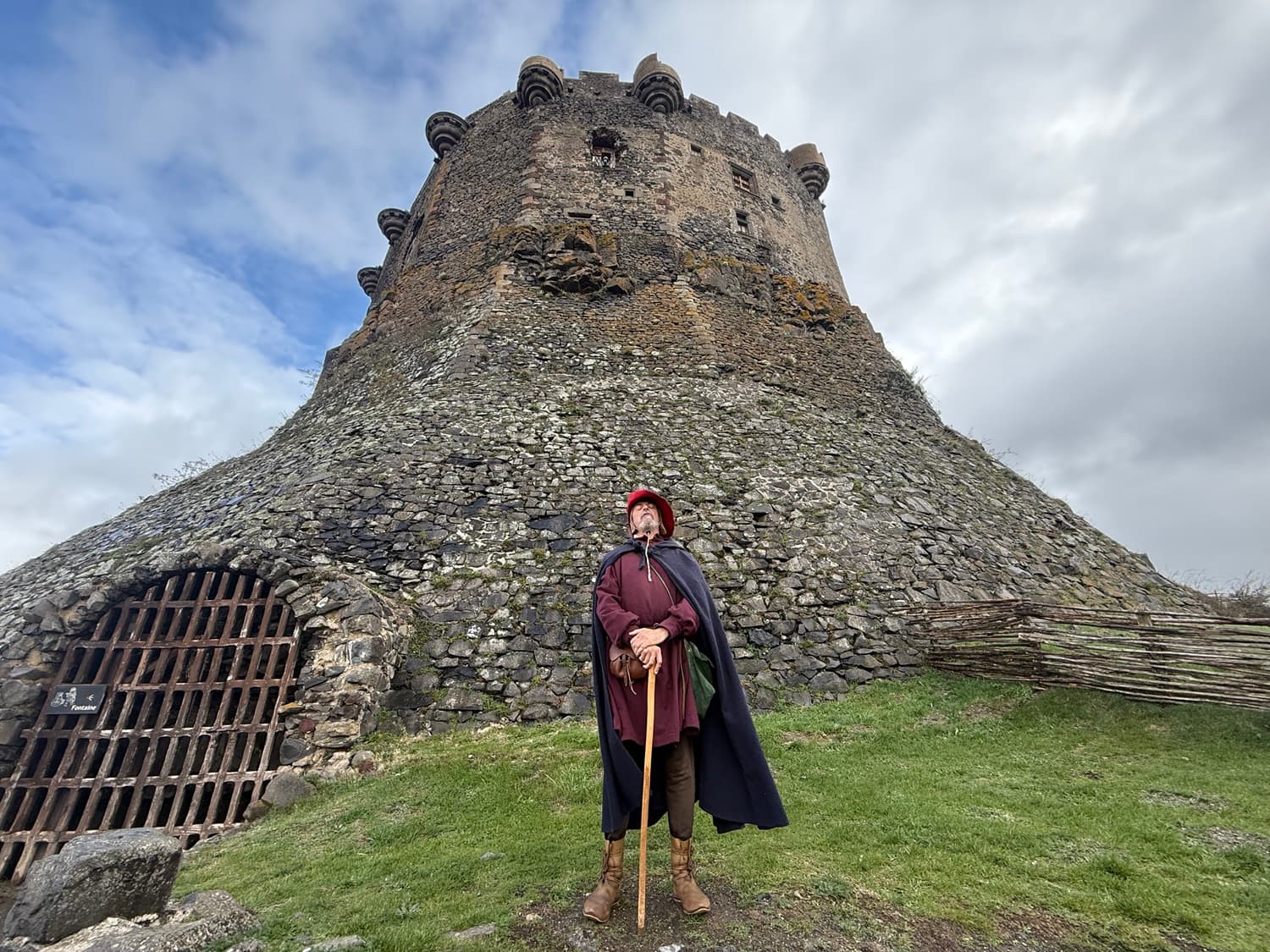 Animation médiévale au château de Murol. Séjour familial en Auvergne : Guide en costume médiéval devant le donjon en pierre du château de Murol.