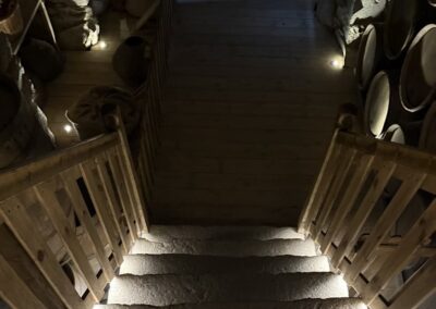 Visite hors des sentiers battus en Auvergne : Escalier en pierre menant aux celliers du château de Murol, paniers et tonneaux en arrière-plan.