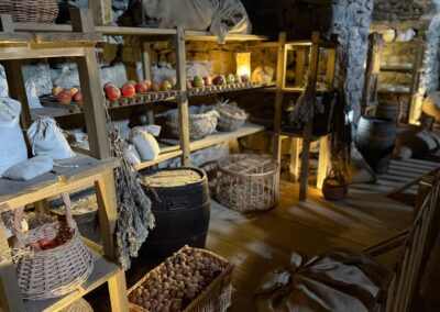 Escapade entre amis en Auvergne : Cellier médiéval du château de Murol avec pommes, noix et provisions sur étagères en bois