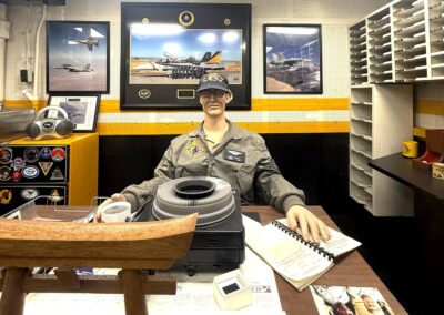 Voyage Incentive à Los Angeles : Bureau reconstitué d'un officier de l'escadron de chasse VFA-192 à bord de l'USS Midway, avec projecteur de diapositives vintage et photos de F/A-18 Hornet.