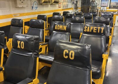 Visite hors des sentiers battus en Californie : Ready Room de l'USS Midway : rangées de fauteuils de « briefing » des pilotes, avec sièges nominatifs pour le commandant, le second et les officiers Admin et Sécurité (San Diego).