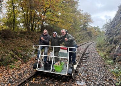 Séjour orignal en Famille : Trois personnes à bord d’un vélo-rail sur une ancienne voie ferrée en Auvergne.