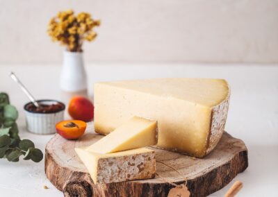 Voyage gastronomique en Auvergne : Meule et morceaux de Cantal AOP sur une planche en bois.